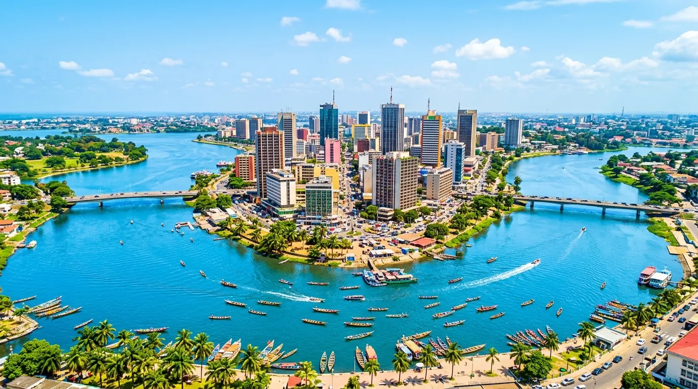 Vue aérienne d’Abidjan en plein jour : le Plateau et la lagune Ébrié sous un ciel bleu.